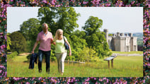 A couple walking through the grounds of Bodelwyddan Castle, a Warner Hotel, with a border featuring the beautiful flowers found in the gardens on the grounds