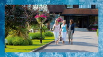 A group of friends walking through the grounds at Sinah Warren, a Warner Hotel. The border depicts the water in the outdoor pool at the hotel.