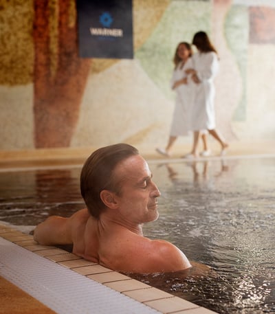 A man enjoying some relaxation time in the spa at a Warner Hotel.